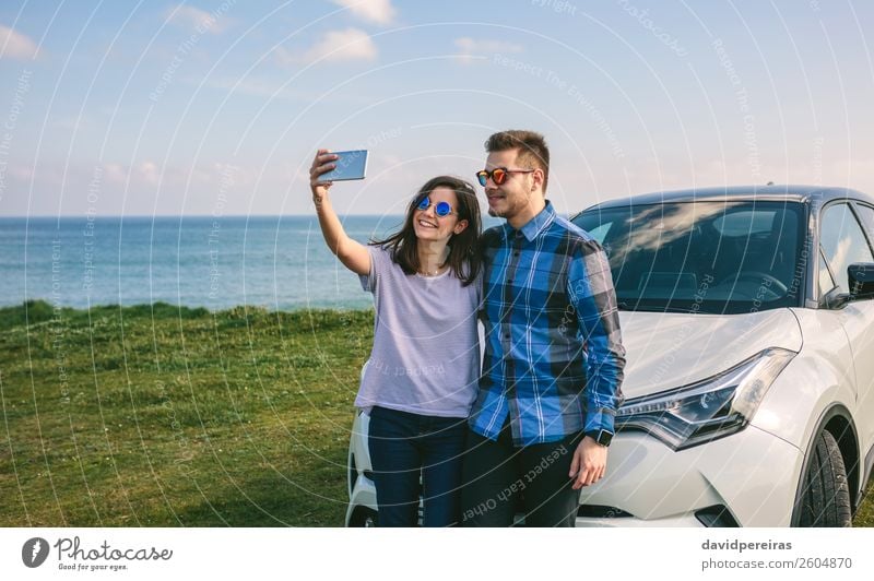 Junges Paar, das einen Selfie auf dem Auto macht. Lifestyle Freude Glück schön Ferien & Urlaub & Reisen Ausflug Meer PDA Mensch Frau Erwachsene Mann Gras Küste