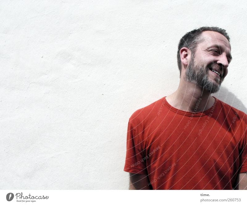H08 – Still One Of Us maskulin Mann Erwachsene Bart 1 Mensch 30-45 Jahre Mauer Wand T-Shirt Lächeln rot weiß schmunzeln Barthaare Kurzhaarschnitt