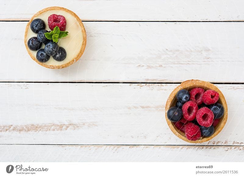 Köstliche Törtchen mit Himbeeren und Heidelbeeren Blaubeeren Frucht Dessert Lebensmittel Foodfotografie lecker Sahne Creme Vanillepudding Snack verglast