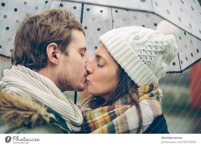 Junges Paar, das sich an einem regnerischen Tag unter dem Regenschirm im Freien küsst. Lifestyle Glück schön Winter Mensch Frau Erwachsene Mann