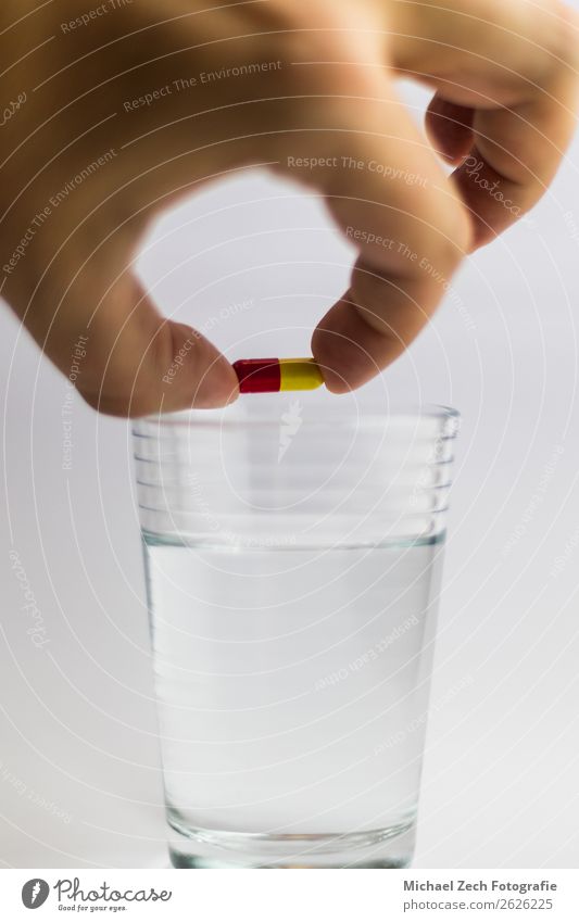 Männer geben eine rot-gelbe Pille in einem Glas Wasser. Schalen & Schüsseln Behandlung Krankheit Medikament Wissenschaften Hand Holz blau rosa weiß Farbe zeigen