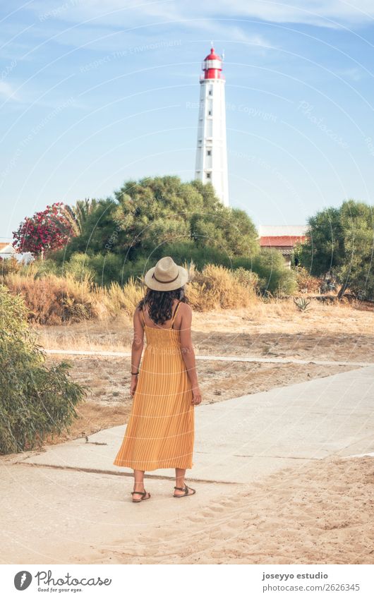 Frau, die mit einem Leuchtturm im Hintergrund geht. Lifestyle Stil Sinnesorgane Erholung Meditation Ferien & Urlaub & Reisen Tourismus Ausflug Sommer Strand
