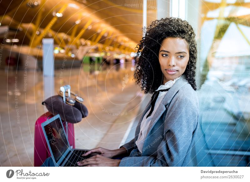 schwarze Frau, die am Flughafen mit dem Laptop arbeitet und am Fenster wartet. Jugendliche Lächeln warten Etage Sonne Sonnenaufgang Sonnenlicht Business
