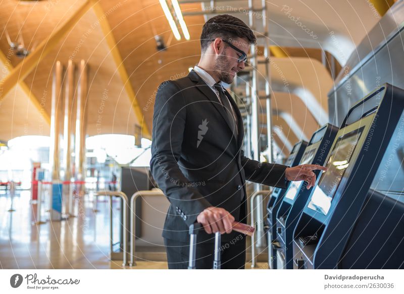 Junger Geschäftsmann beim Selbstchecken in einer Maschine am Flughafen Mann Ferien & Urlaub & Reisen kariert Aufschlag Kiosk Check-in Eintrittskarte