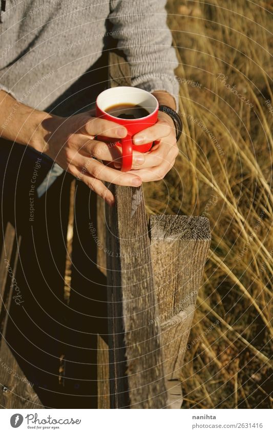 Mann hält eine Tasse Kaffee auf einer Holzbank. Frühstück Getränk trinken Heißgetränk Kakao Tee Lifestyle Gesundheit Gesunde Ernährung Wellness Wohlgefühl