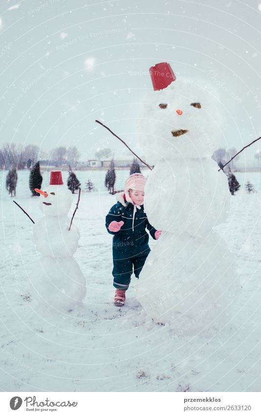 Kleines Mädchen macht einen Schneemann Lifestyle Freude Glück Winter Kind Mensch 1 3-8 Jahre Kindheit Schneefall Bekleidung genießen machen klein niedlich weiß