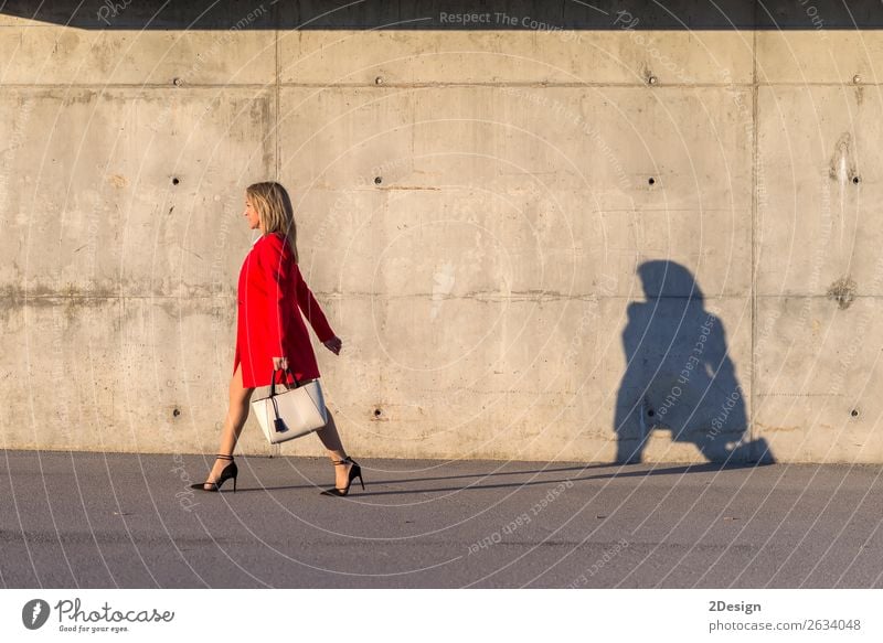 Blonde Frau in roter Jacke, die auf der Straße geht. Lifestyle schön Business feminin Erwachsene Hemd Rock Schuhe Damenschuhe blond schwarz weiß Geschäftsfrau