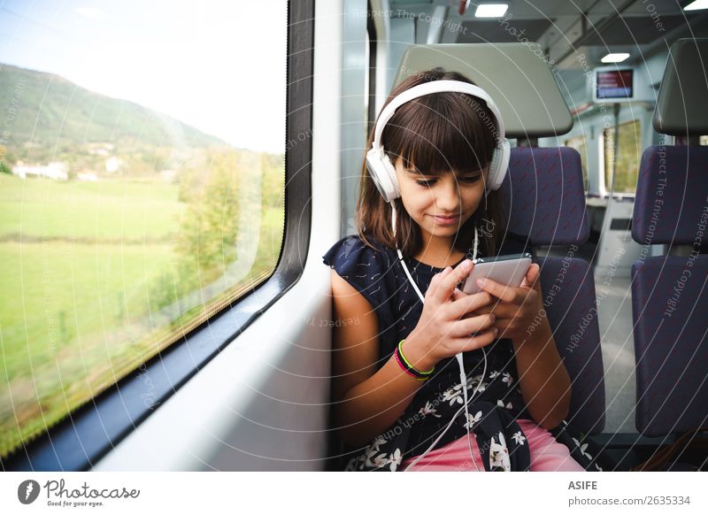 Kleines Mädchen mit Kopfhörer und Smartphone im Zug unterwegs Freude Glück schön Freizeit & Hobby Ferien & Urlaub & Reisen Ausflug Musik Kind Headset PDA