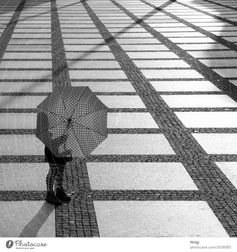Frau steht im Gegenlicht hinter einem geöffneten Regenschirm auf einem großen Platz mit kariertem Boden Mensch feminin Beine Fuß 1 45-60 Jahre Erwachsene