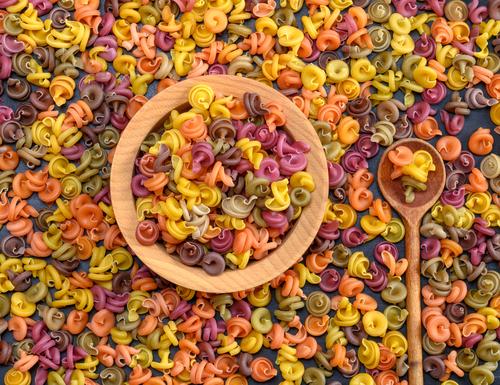 mehrfarbige spiralförmige Rohteigwaren-Fusilli in einer Holzschale Teigwaren Backwaren Ernährung Abendessen Diät Schalen & Schüsseln Löffel Essen frisch braun