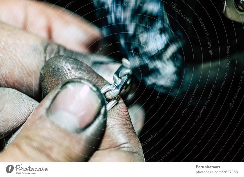 Juwelier, der in seiner Werkstatt an einer Silberkette arbeitet. Beruf Fabrik Handwerk Finger Pflanze Schmuck Ring Aktenordner Metall dunkel rot anketten gold