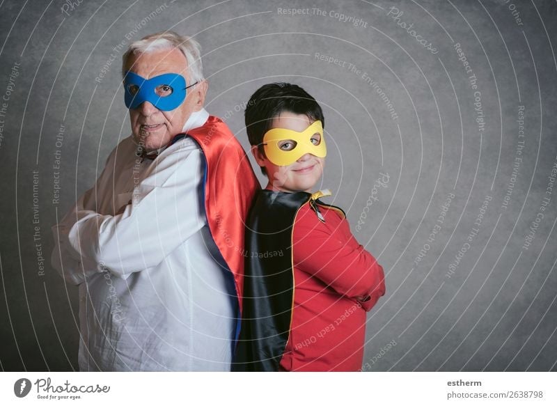Grossvater mit Enkel als Superheld verkleidet auf grauem Hintergrund Lifestyle Freude Abenteuer Feste & Feiern Karneval Jahrmarkt Erfolg Ruhestand Mensch
