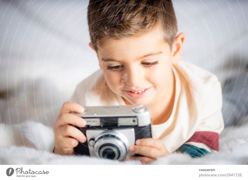 Schöner Junge mit einer Fotokamera im Bett. Lifestyle Freude Glück schön Gesicht Ferien & Urlaub & Reisen Kind Technik & Technologie Mensch Baby Kleinkind