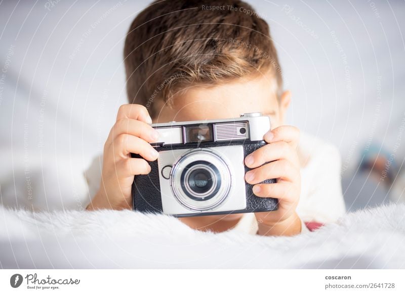 Schöner Junge mit einer Fotokamera im Bett. Lifestyle Freude Glück schön Gesicht Ferien & Urlaub & Reisen Raum Schlafzimmer Kind Technik & Technologie Mensch