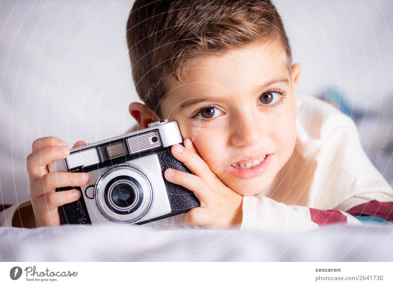 Schöner Junge mit einer Fotokamera im Bett. Lifestyle Freude Glück schön Gesicht Haus Raum Schlafzimmer Bildung Kind Azubi Student Technik & Technologie Mensch