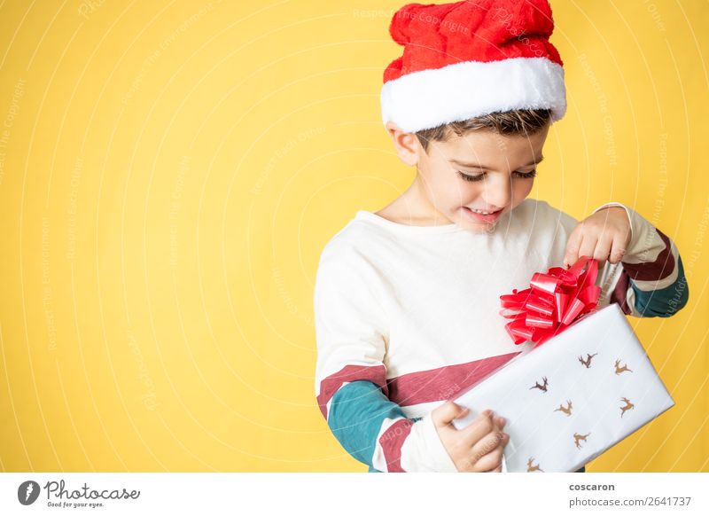Kleines Kind mit einem Geschenk auf gelbem Hintergrund am Weihnachtstag. Lifestyle kaufen Stil Design Freude Glück schön Winter Feste & Feiern