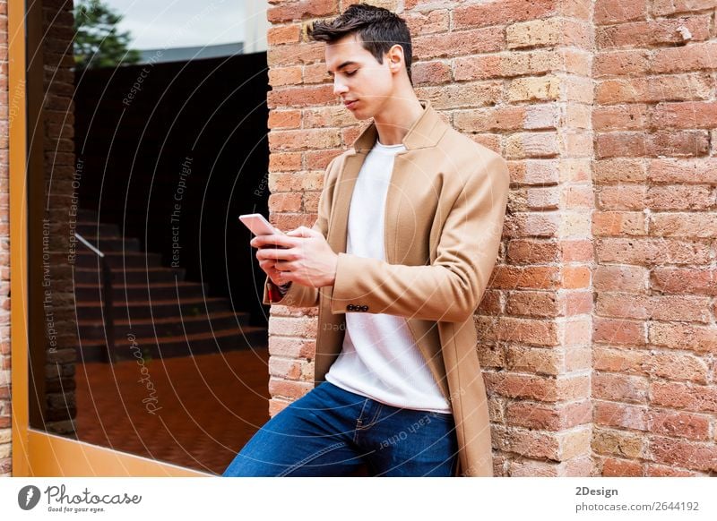 Moderner junger Mann mit Handy auf der Straße. elegant Stil schön Haare & Frisuren Winter Telefon PDA Mensch Erwachsene Jugendliche Herbst Bekleidung Jeanshose