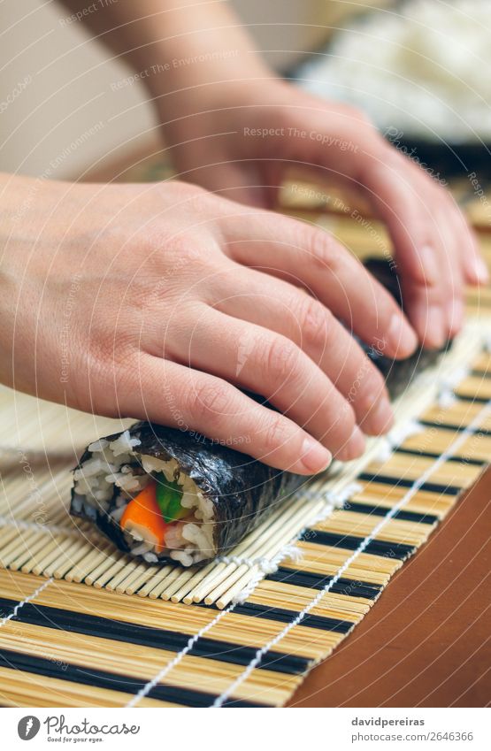 Frau Küchenchefin Hände rollen japanisches Sushi auf. Diät Mensch Erwachsene Hand machen frisch rollierend vorbereitend Kalifornische Walze Krabbenstock Avocado