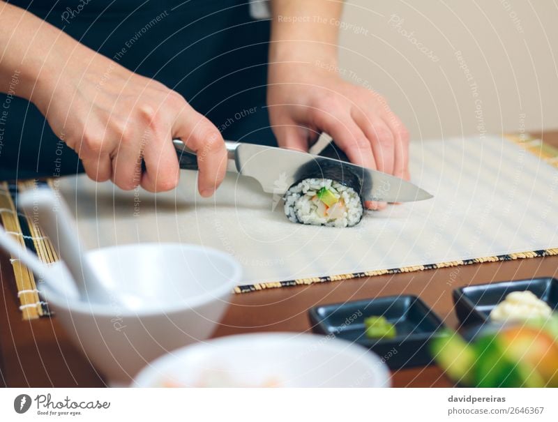Nahaufnahme von einer Köchin, die japanische Sushi-Rolle schneidet. Meeresfrüchte Mittagessen Diät Restaurant Frau Erwachsene Hand machen frisch Küchenchef