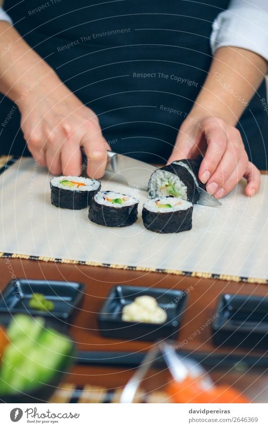 Köchin beim Schneiden von japanischer Sushi-Rolle Meeresfrüchte Abendessen Diät Restaurant Frau Erwachsene Hand machen frisch Tradition rollen geschnitten