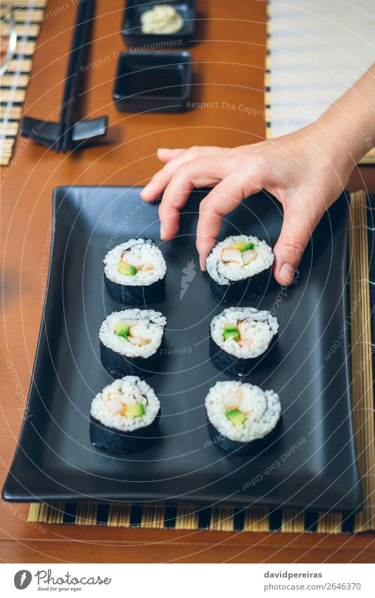 Köchin, die japanische Sushi-Rollen auf ein Tablett legt. Teller Restaurant Frau Erwachsene Hand Platz machen frisch schwarz Küchenchef Platzierung nehmen