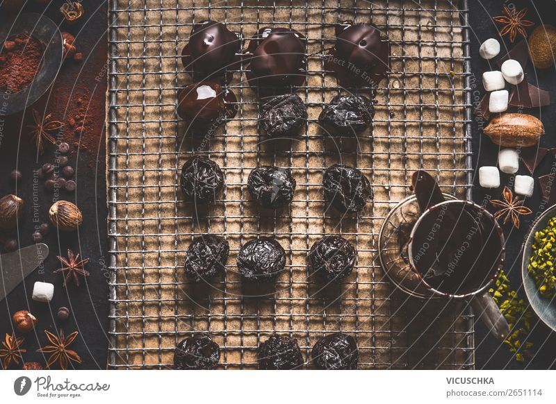 Hausgemachte Pralinen und Trüffel auf dunklem Küchentisch Hintergrund mit schmelzender Schokolade und Zutaten, Ansicht von oben selbstgemacht Kakao dunkel Tisch