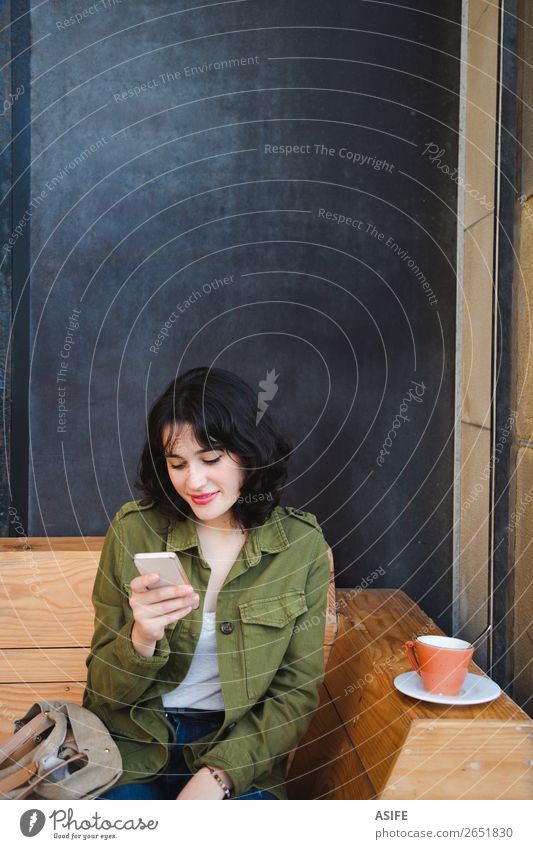 Junge Frau beim Kaffeetrinken mit dem Handy Glück schön Freizeit & Hobby Tafel Telefon PDA Technik & Technologie Erwachsene Terrasse Jeanshose Jacke brünett