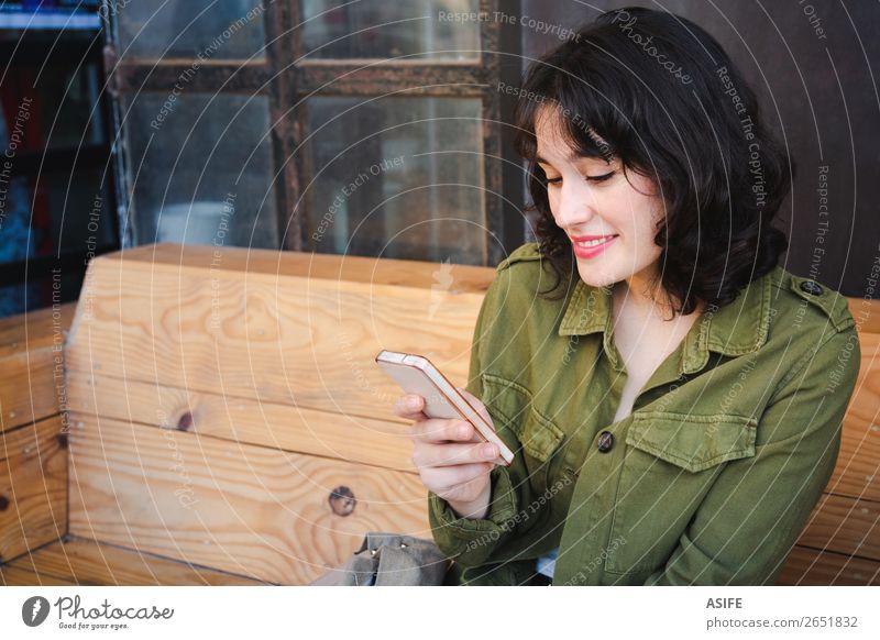Lächelnde junge Frau, die ihr Smartphone in einer Cafébar benutzt. Lifestyle Glück schön Freizeit & Hobby Tafel Telefon Handy PDA Technik & Technologie