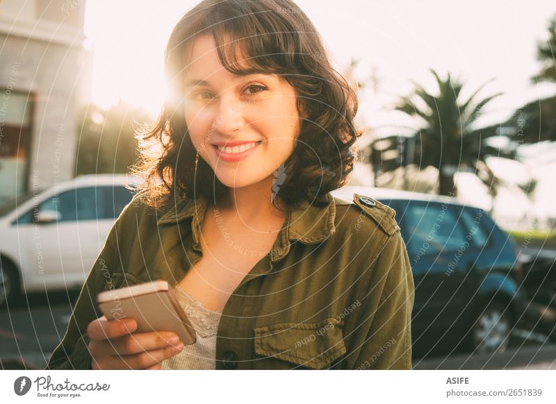 Schöne Frau mit einem Smartphone auf der Straße bei Sonnenuntergang. Glück schön Freizeit & Hobby Telefon Handy PDA Technik & Technologie Erwachsene Herbst