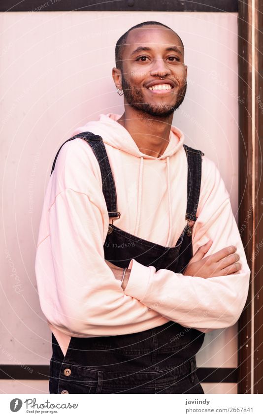 Junger schwarzer Mann in Freizeitkleidung lächelt vor einem rosafarbenen städtischen Hintergrund Lifestyle Glück schön Mensch maskulin Junger Mann Jugendliche