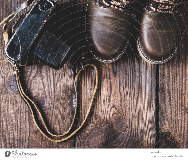 lederne braune Schuhe und eine alte Vintage-Kamera. Stil Design Fotokamera Fuß Mode Bekleidung Leder Holz Top Aussicht klassisch Hintergrund altehrwürdig lässig