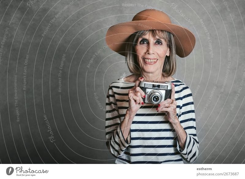 Porträt der lächelnden älteren Frau mit Vintage-Fotokamera auf grauem Hintergrund Lifestyle Freude Freizeit & Hobby Ferien & Urlaub & Reisen Tourismus Ausflug