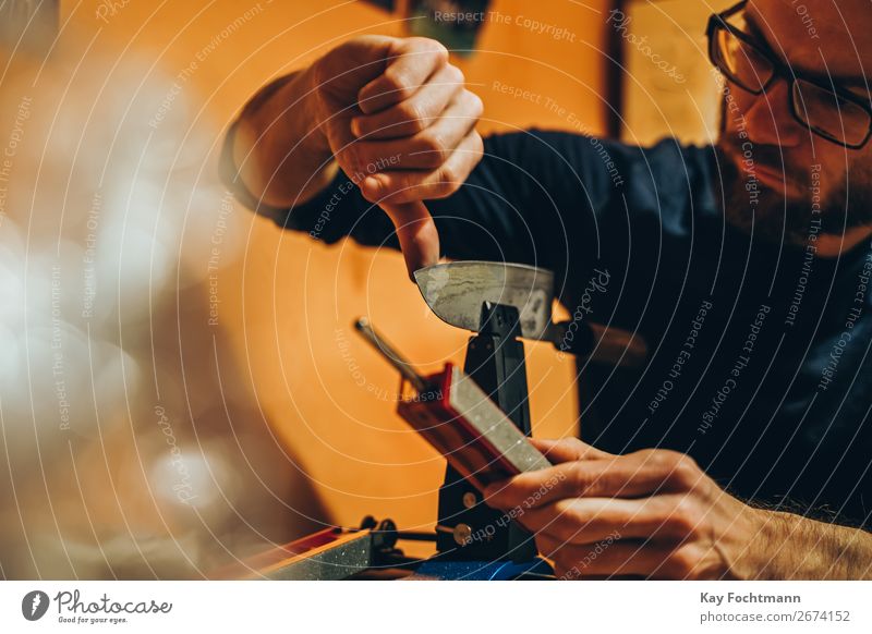 Mann schärft Messer Schleifmittel Vollbart Klinge Nahaufnahme Konzentration Essen zubereiten Handwerk Kunsthandwerker geschnitten Kompetenz Grinden