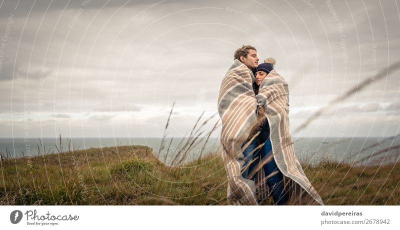 Junges Paar, das sich an einem kalten Tag unter der Decke im Freien umarmt. Lifestyle schön ruhig Meer Winter Berge u. Gebirge Frau Erwachsene Mann Natur