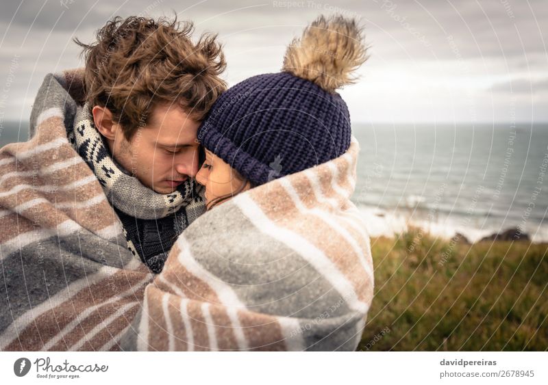 Junges Paar, das sich an einem kalten Tag unter der Decke im Freien umarmt. Lifestyle Glück schön Meer Winter Berge u. Gebirge Frau Erwachsene Mann Natur Himmel