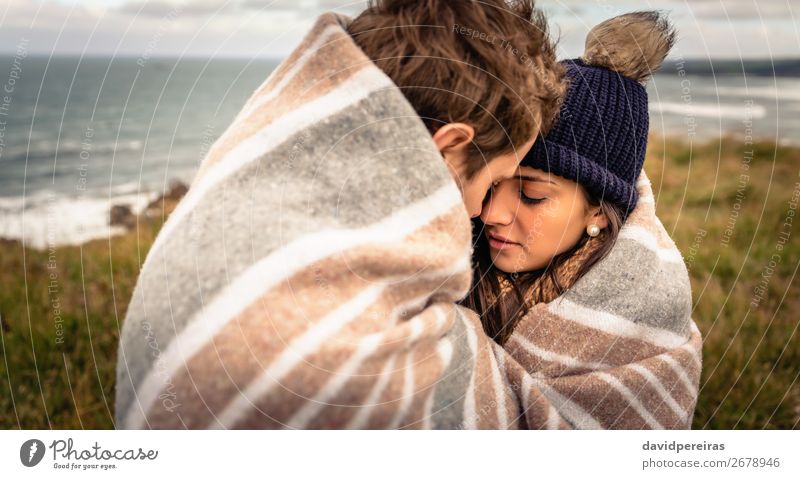 Junges Paar, das sich an einem kalten Tag unter der Decke im Freien umarmt. Lifestyle Glück schön Meer Winter Berge u. Gebirge Frau Erwachsene Mann Natur Himmel