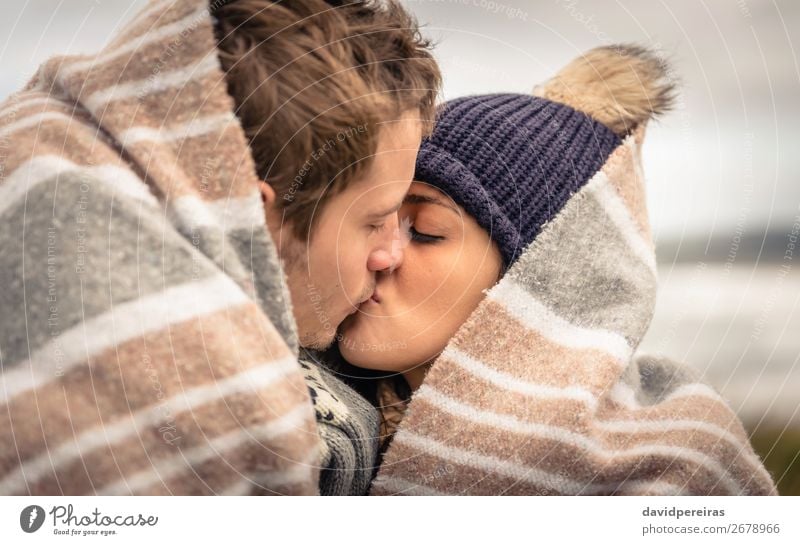 Junges Paar, das sich an einem kalten Tag unter der Decke im Freien küsst. Lifestyle Glück schön Meer Winter Berge u. Gebirge Frau Erwachsene Mann Natur Himmel