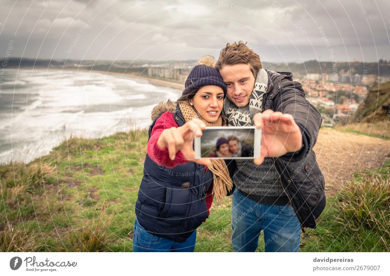Paar nimmt selfie Foto in Smartphone mit Meer und dunklen bewölkten Himmel auf dem Hintergrund Lifestyle Glück Strand Winter Telefon PDA Fotokamera Frau