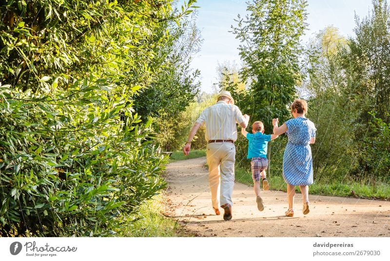 Großeltern und Enkelkind springen auf Naturpfad Lifestyle Freude Glück Freizeit & Hobby Kind Junge Frau Erwachsene Mann Eltern Großvater Großmutter