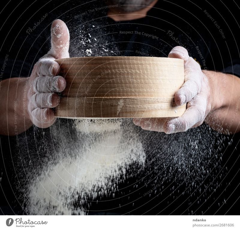 Mann siebt weißes Weizenmehl durch ein Holzsieb. Teigwaren Backwaren Brot Ernährung Küche Koch Mensch Erwachsene Hand Sieb Bewegung machen frisch schwarz Mehl