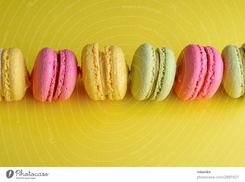 Dessert Makronen liegt in der Mitte in einer Reihe. Kuchen Süßwaren hell gelb grün rosa Farbe Mandel Hintergrund backen Bäckerei Biskuit farbenfroh Sahne