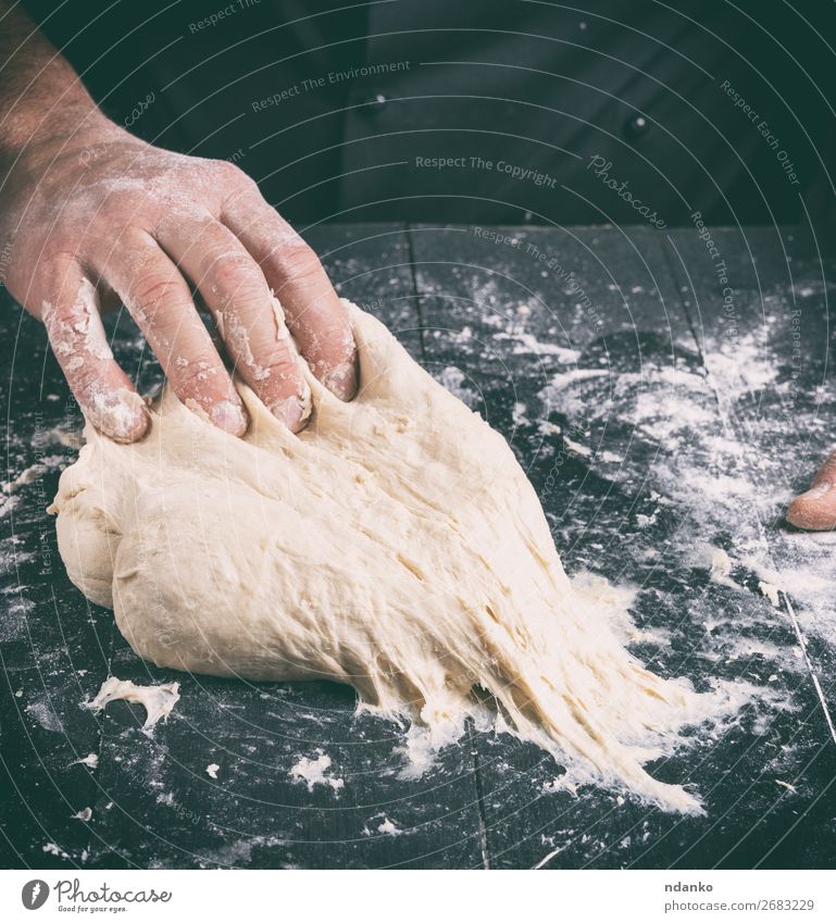 Koch in schwarzer Jacke knet Teig Teigwaren Backwaren Brot Ernährung Haut Tisch Küche Mensch Mann Erwachsene Hand Holz machen weiß Tradition backen Bäcker