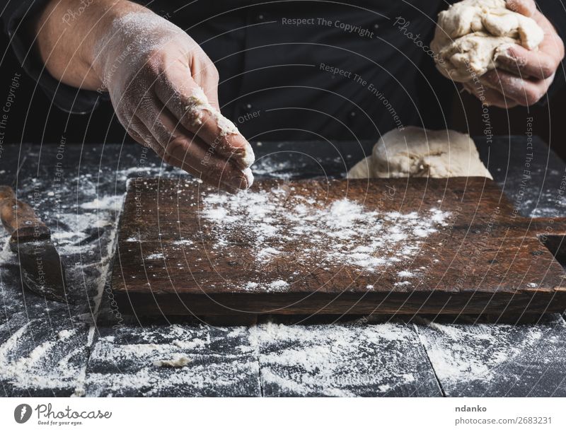Koch in schwarzer Jacke knet Teig Teigwaren Backwaren Brot Ernährung Haut Tisch Küche Mensch Mann Erwachsene Hand Holz machen weiß Tradition backen Bäcker
