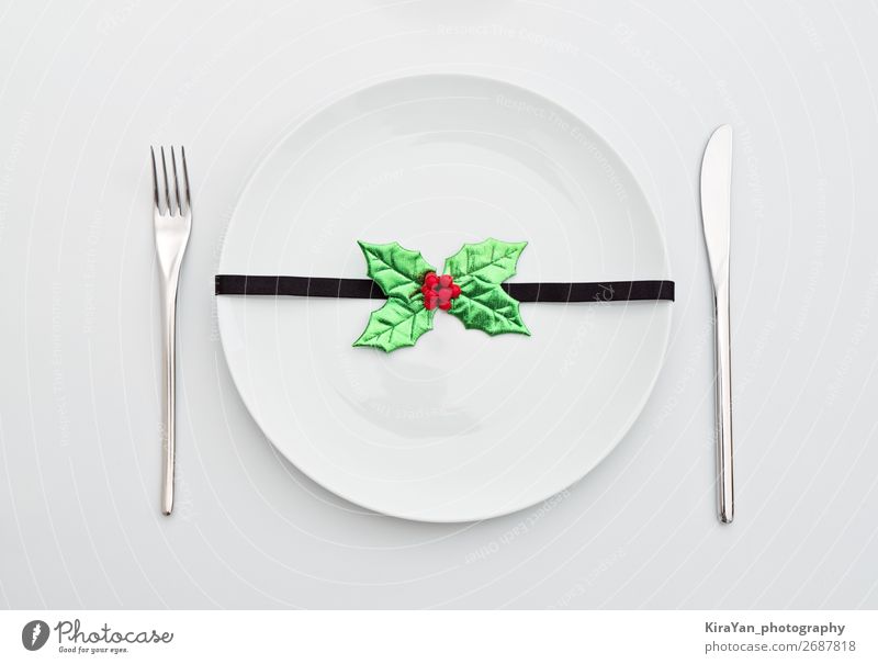 Weihnachtsdekoration mit Stechpalmenblättern auf weißem Teller Abendessen Besteck Gabel Dekoration & Verzierung Restaurant Feste & Feiern Weihnachten & Advent