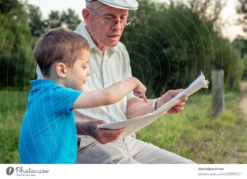 Senior Mann und Kind lesen eine Zeitung im Freien. Lifestyle Glück Freizeit & Hobby Schule Mensch Junge Erwachsene Eltern Großvater Familie & Verwandtschaft