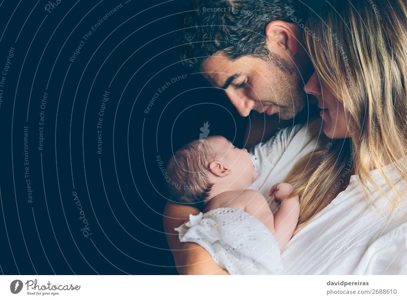 Paar umarmt und Blick auf ihr Neugeborenes über dunklen Hintergrund Lifestyle Glück schön Kind Mensch Baby Kleinkind Frau Erwachsene Mann Eltern Mutter Vater