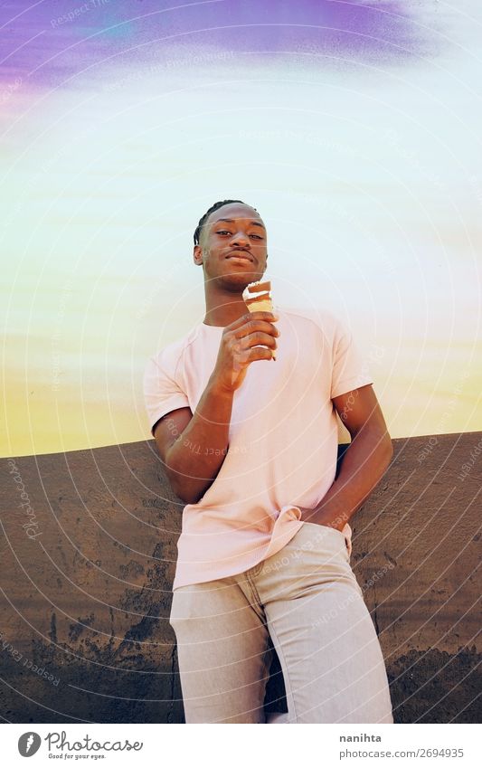 Ein junger, gutaussehender Mann hält und isst einen Eisbecher. Speiseeis Stil Glück Sommer Sonnenbad Mensch maskulin Erwachsene Jugendliche T-Shirt Hemd