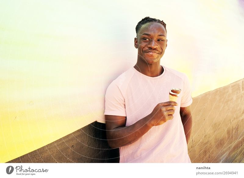 Junger, gutaussehender Mann hält ein Eis in der Hand. Speiseeis Stil Glück Sommer Sonnenbad Mensch Junger Mann Jugendliche Erwachsene T-Shirt Hemd