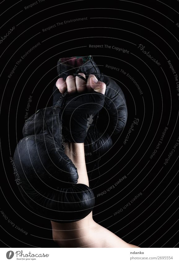 Die Männerhand hält ein Paar alte schwarze Lederboxhandschuhe. Lifestyle Fitness Sport Sportler Erfolg Mann Erwachsene Hand Handschuhe hängen dunkel stark braun