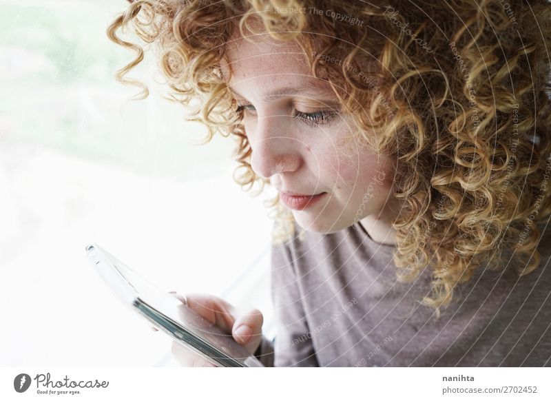 Porträt einer jungen Frau schaut auf ihr Smartphone. Stil schön Haare & Frisuren Haut Gesicht Telefon Handy PDA Technik & Technologie Unterhaltungselektronik